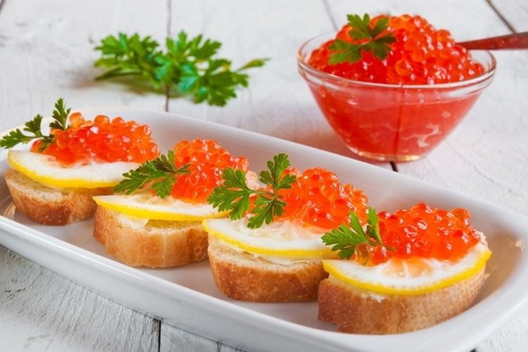 Canapes with red caviar, curd cheese and lemon