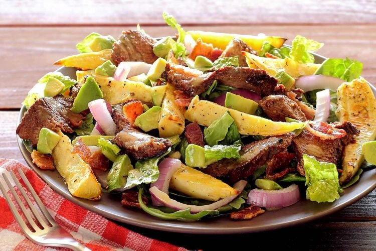 Salad with fried potatoes, beef, pigtail cheese and herbs