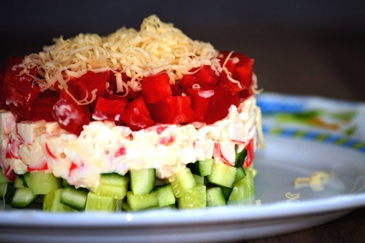Layered salad of cheese, crab meat and fresh vegetables